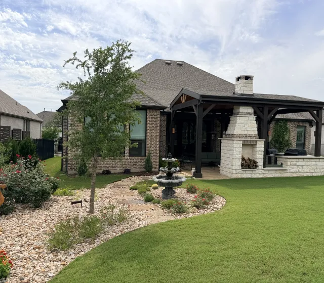 Custom outdoor living space with a stone fireplace and covered patio in Austin, TX