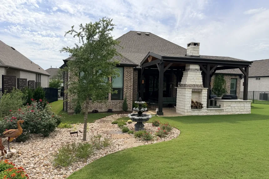 Covered outdoor living pavilion in Austin, TX with a stone fireplace, seating area, and built-in grill station