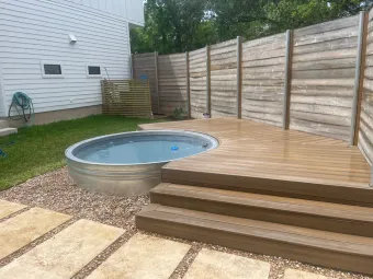 Wood deck with built-in stock-tank pool and paver walkway in an Austin backyard