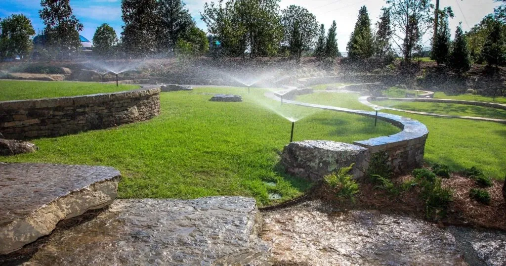 Sprinkler irrigation system watering a stone-walled Austin backyard