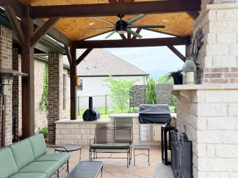 Wide interior view of an outdoor living pavilion with seating, fireplace, and outdoor kitchen