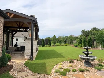 Austin backyard with covered outdoor living pavilion, garden fountain, and landscaped lawn
