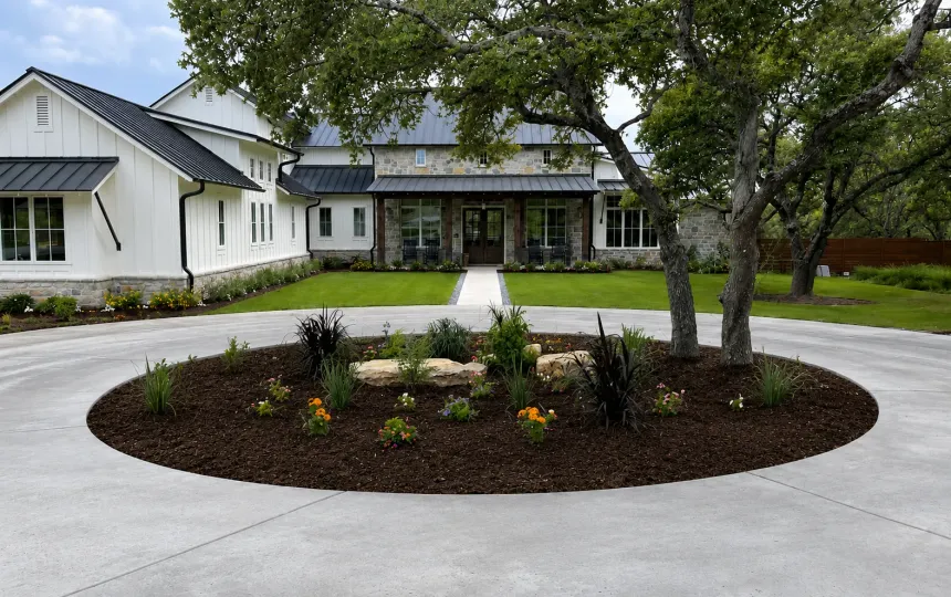 Circular driveway planting island with layered mulch beds in front of an Austin, TX home