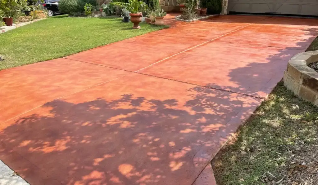 Concrete driveways installation with a smooth red finish in a residential Austin property, providing enhanced curb appeal and durability.