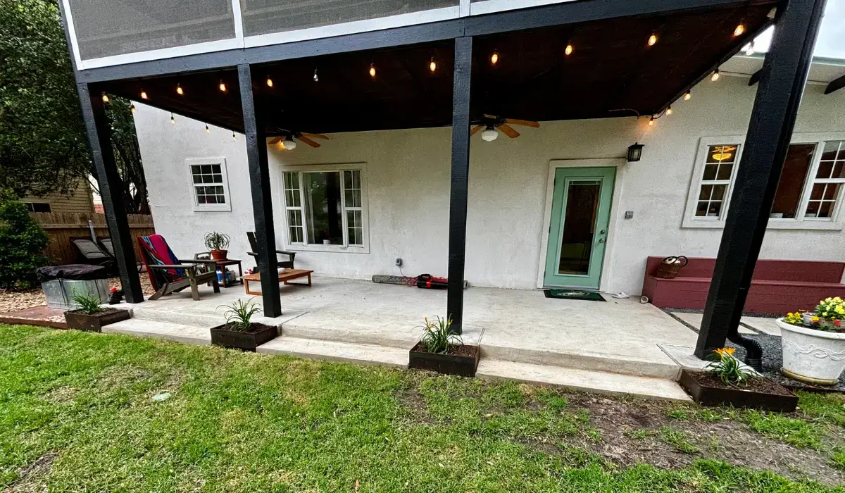 Covered veranda with modern outdoor furniture, lighting, and lush landscaping for relaxing outdoor living.