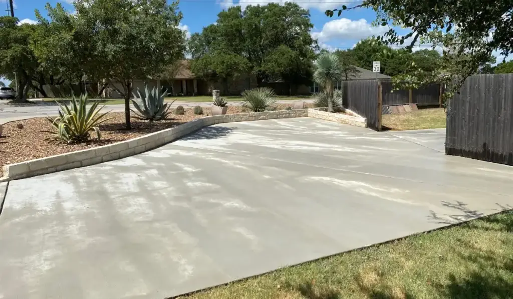 Eco-friendly hardscaping with a concrete driveway and sustainable landscaping featuring drought-tolerant plants.