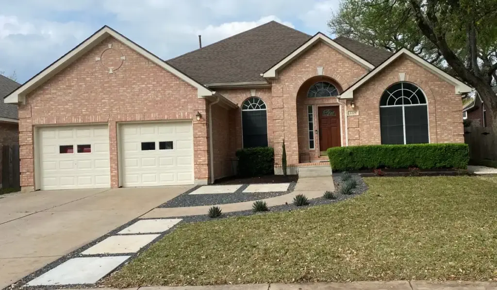 Austin driveways and pathways featuring a concrete driveway, modern stepping stone walkway, landscaped yard, and a brick home.