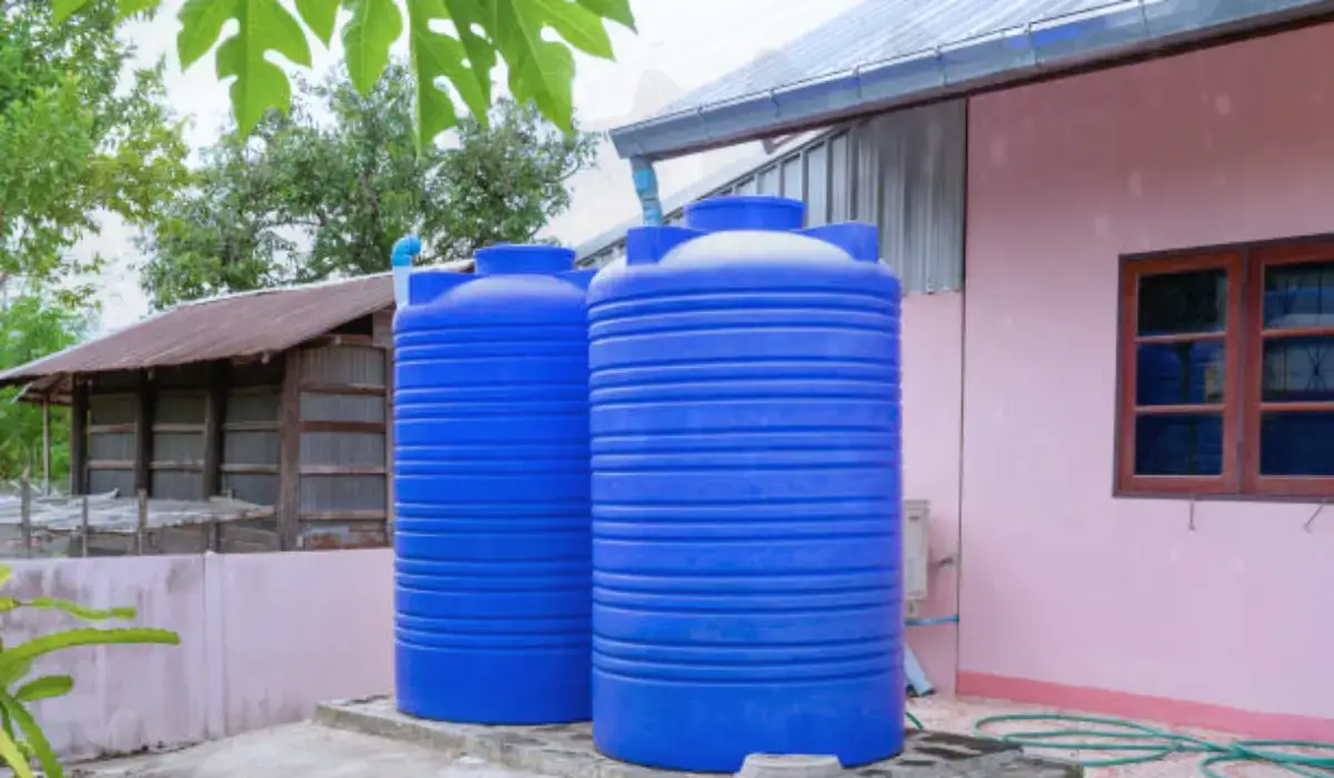 Rainwater collection systems with two blue tanks connected to roof gutters beside a residential house.