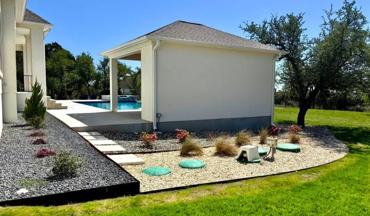 Completed landscape renovation project in Austin showing a modern backyard with a raised patio, stone walkway, and newly planted greenery.