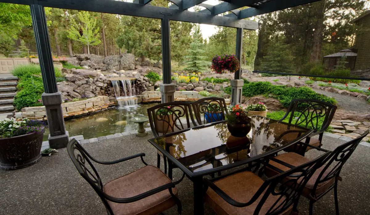 Water features Austin backyard patio with pond and waterfall integrated into outdoor seating and landscape design.
