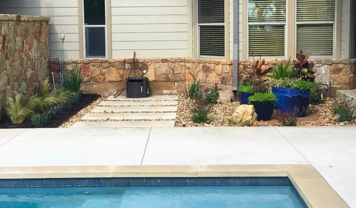 Detail view of poolside landscapes in Austin featuring stone edging, gravel accents, and drought-tolerant plants arranged for low maintenance.