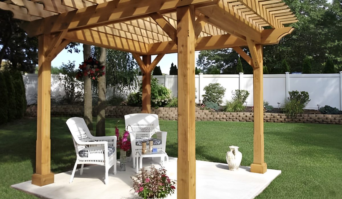Wooden pergola in a beautifully landscaped outdoor living spaces with white chairs and green lawn